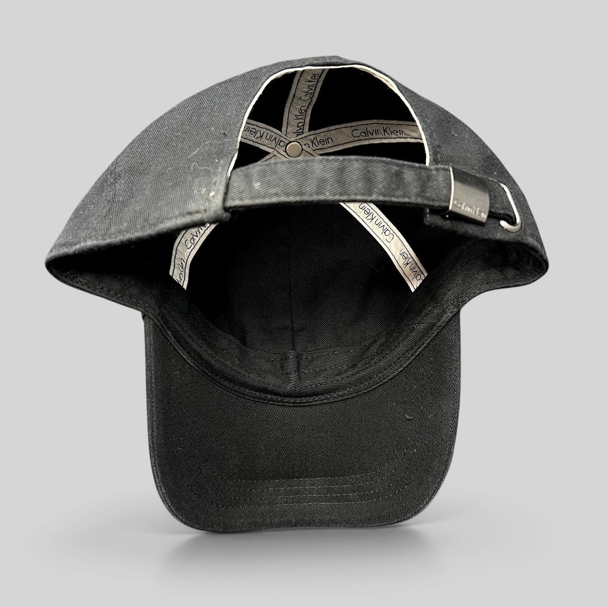 Raree Finds vintage black Calvin Klein strapback hat showing interior branded taping and metal buckle closure