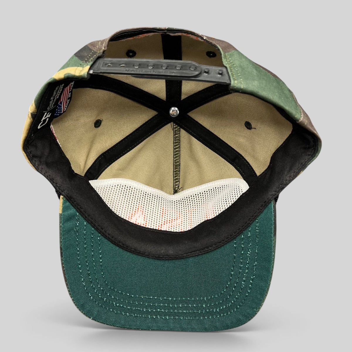 Raree Finds woodland camo snapback hat interior view showing black plastic snap closure and green brim underside