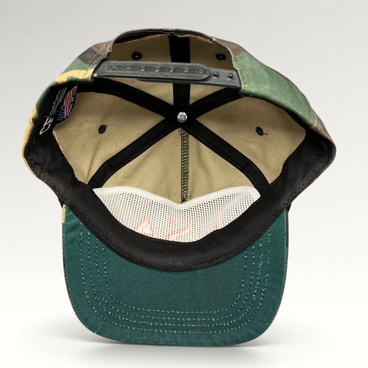 Raree Finds woodland camo snapback hat interior view showing black plastic snap closure and green brim underside