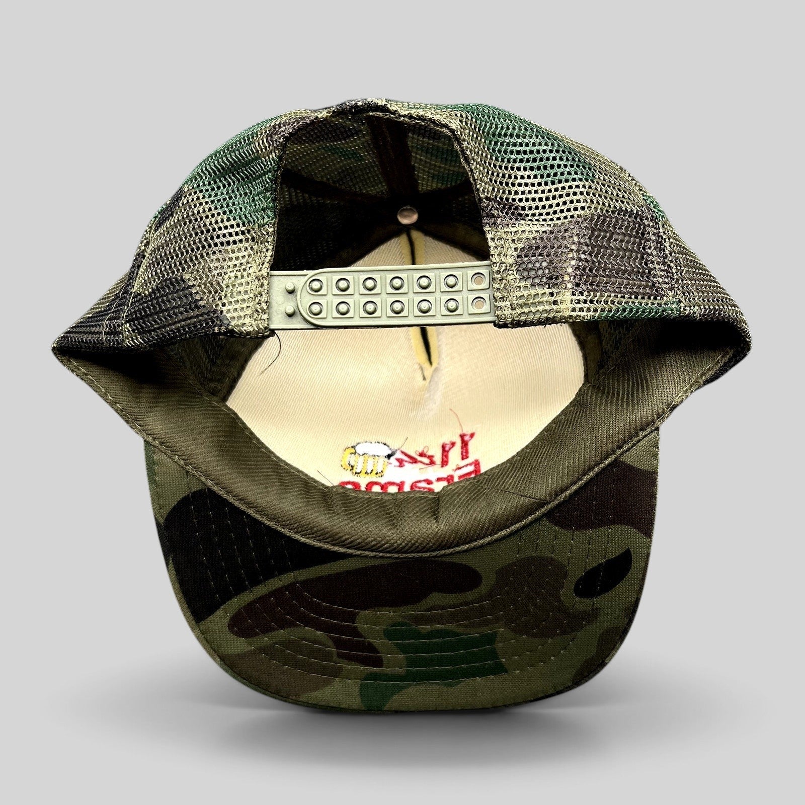 Raree Finds vintage 11th Frame trucker hat with woodland camo brim, olive mesh back, and adjustable snapback closure.