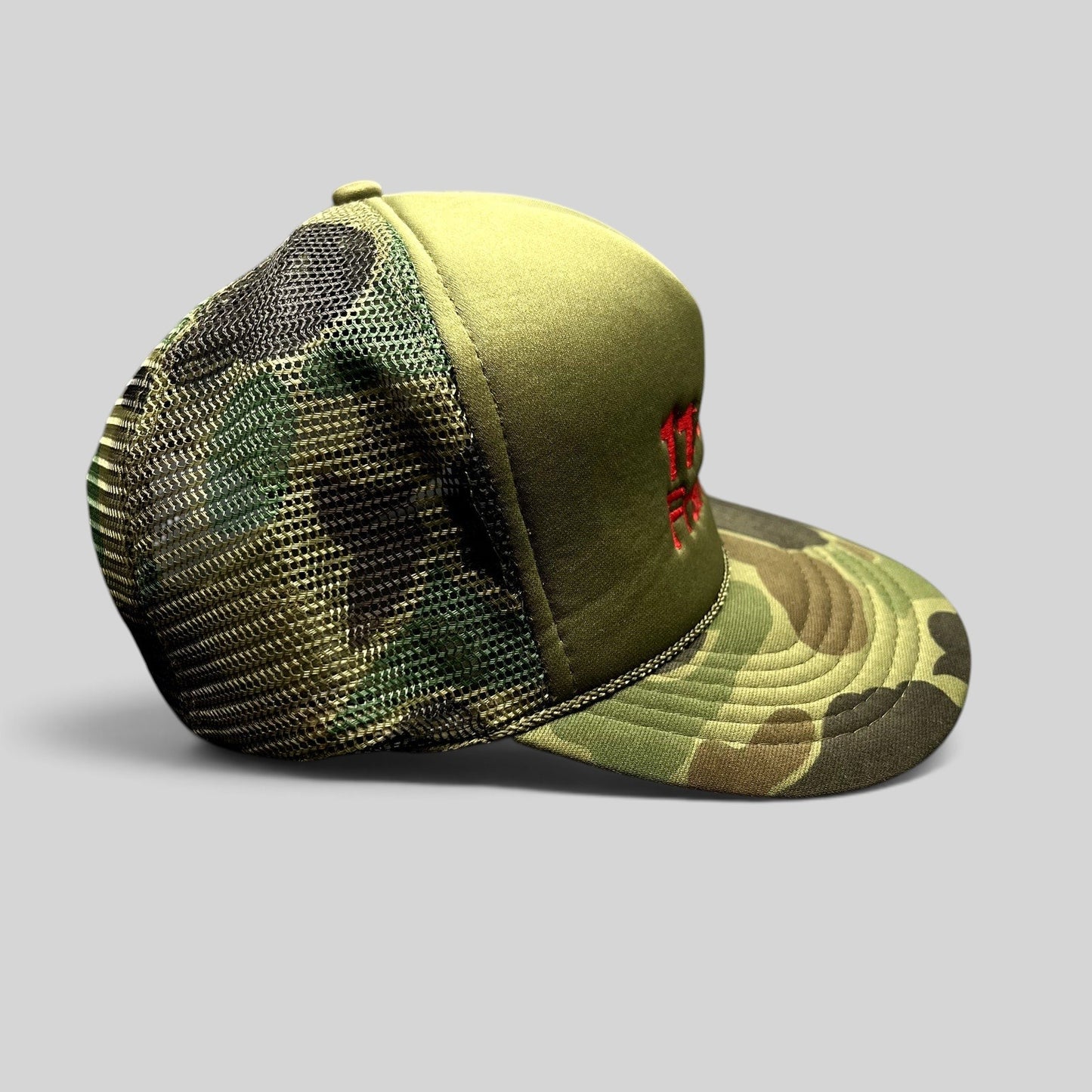 Raree Finds vintage 11th Frame trucker hat with olive foam front, woodland camo brim, and mesh back.