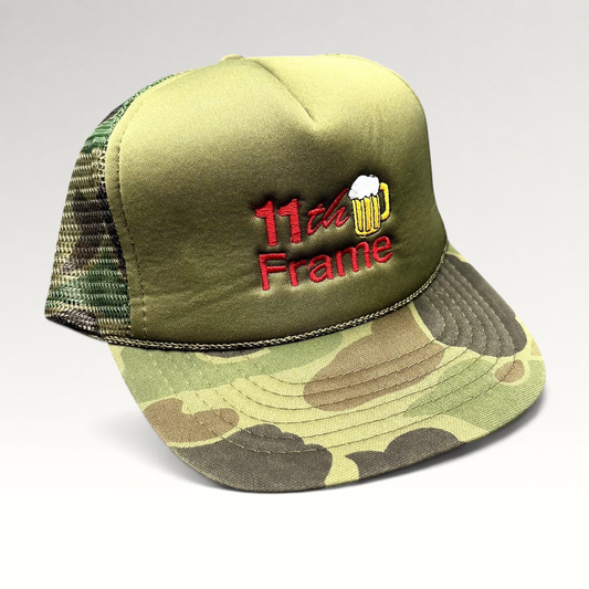 Raree Finds vintage 11th Frame trucker hat with olive foam front, woodland camo brim, and embroidered beer mug logo.