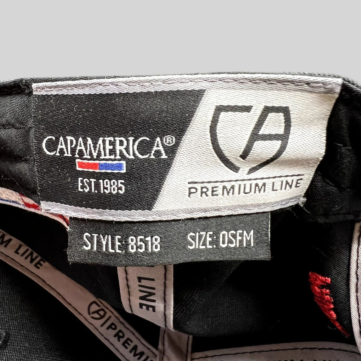 Raree Finds Cap America Premium Line interior tag showing style 8518 and OSFM size on a black racing snapback hat