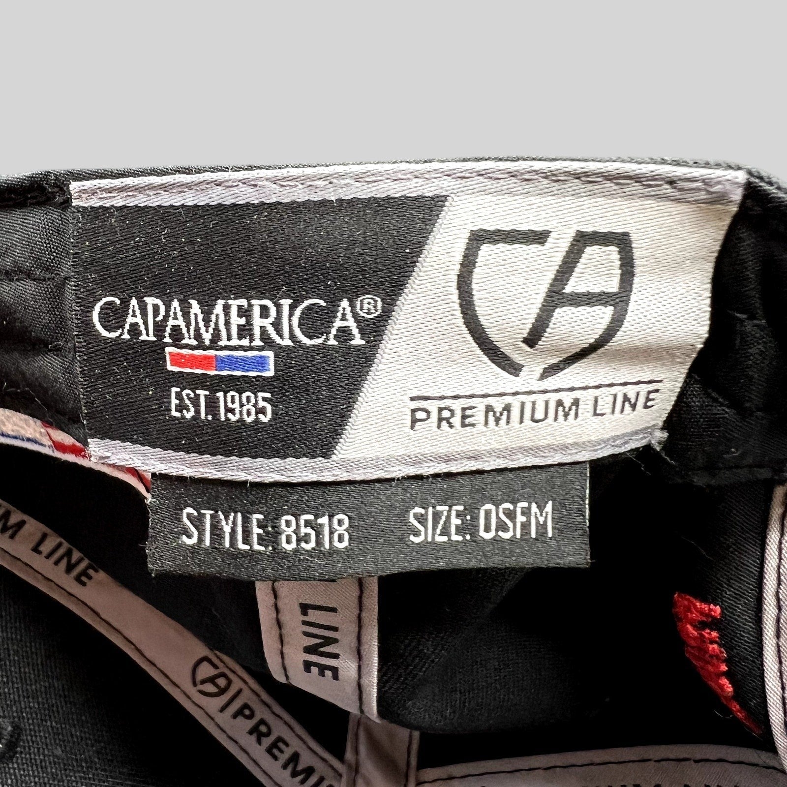 Raree Finds Cap America Premium Line interior tag showing style 8518 and OSFM size on a black racing snapback hat
