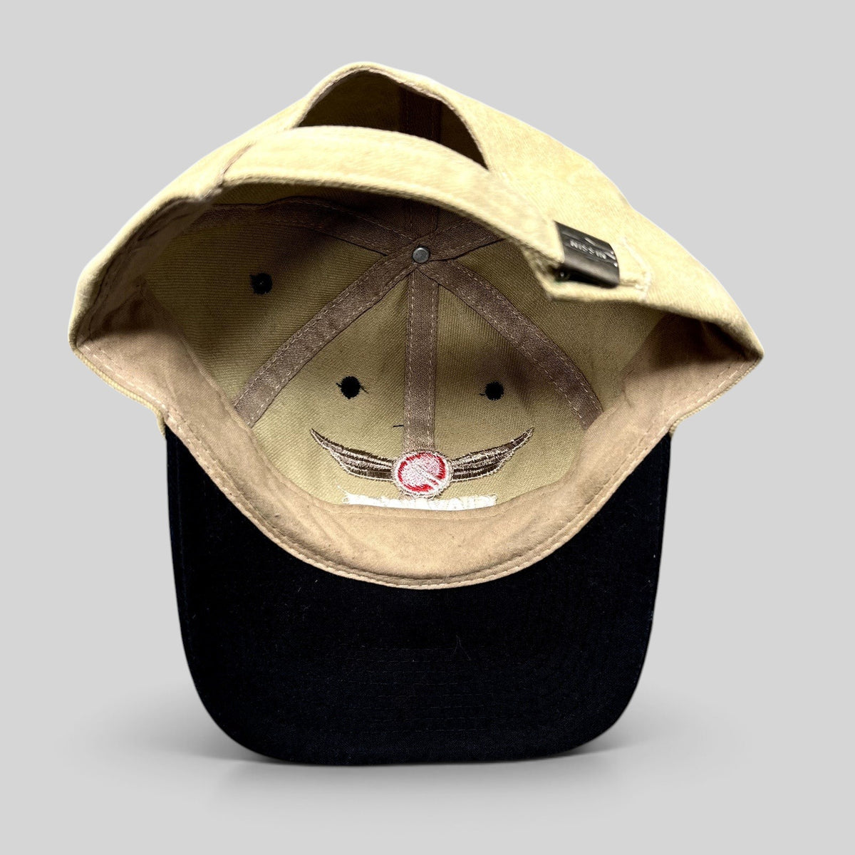 Raree Finds vintage Clay Lacy Aviation strapback cap with tan cotton crown, black brim, and interior winged logo.