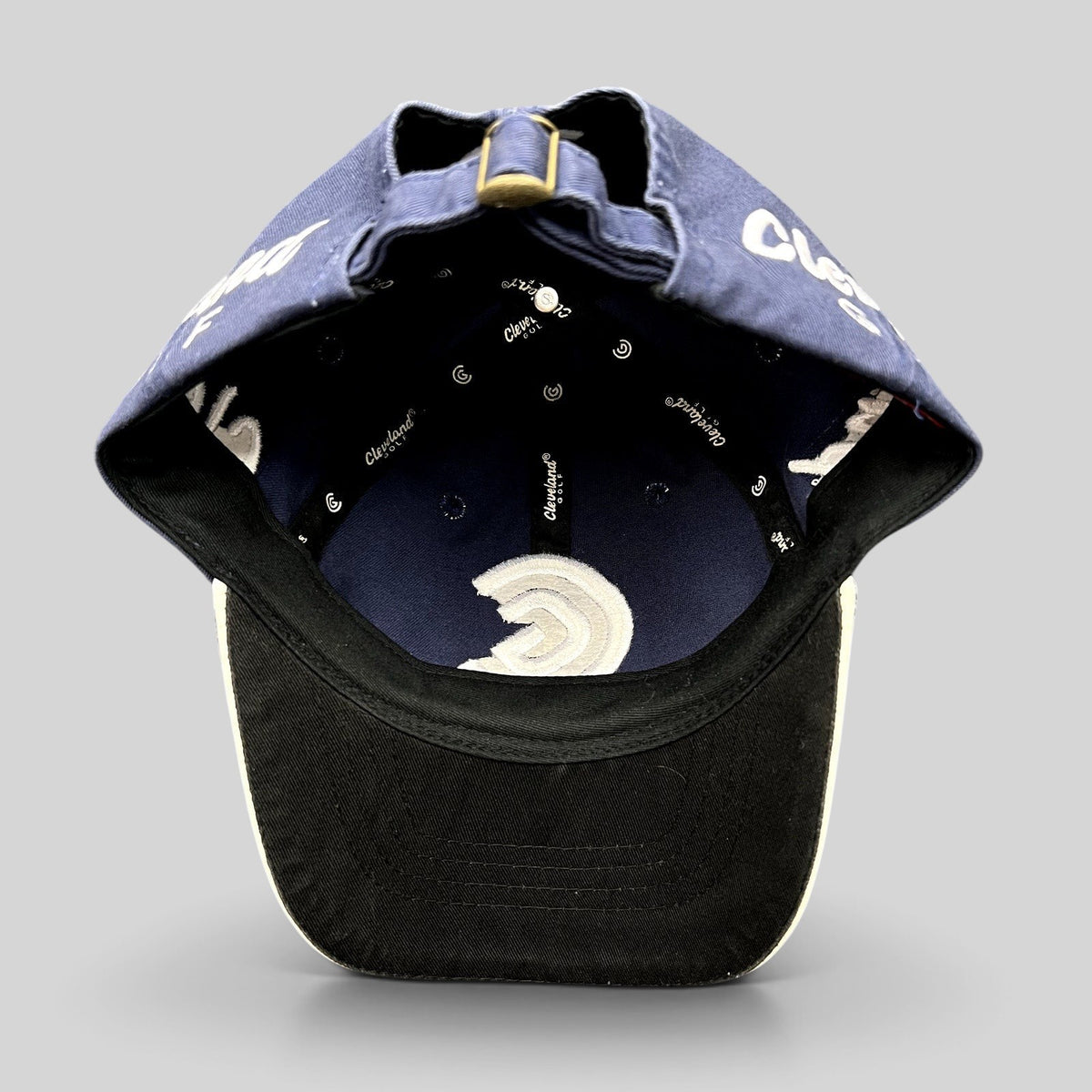 Raree Finds navy blue Cleveland Golf strapback hat interior view showing branded lining and adjustable brass buckle
