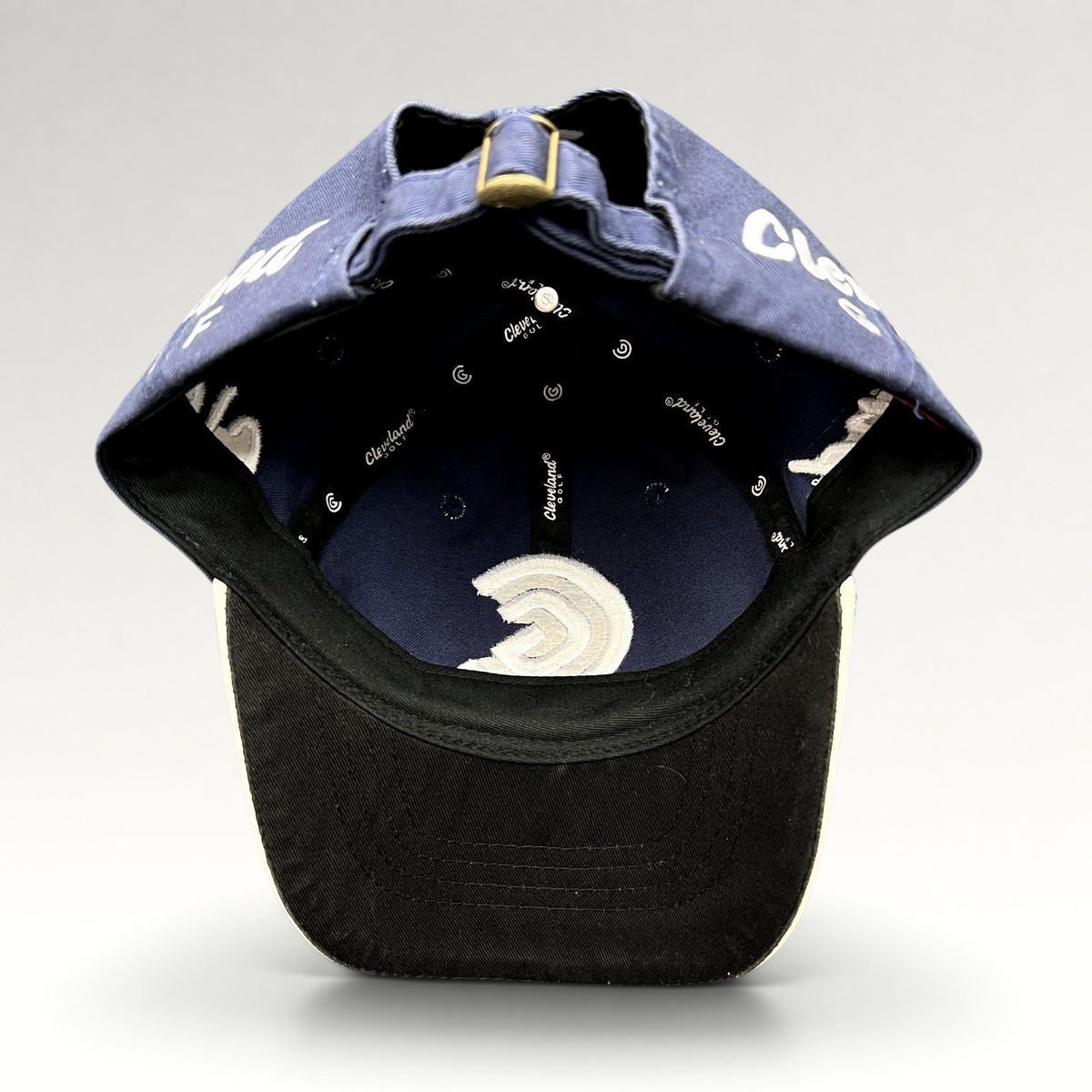 Raree Finds navy blue Cleveland Golf strapback hat interior view showing branded lining and adjustable brass buckle