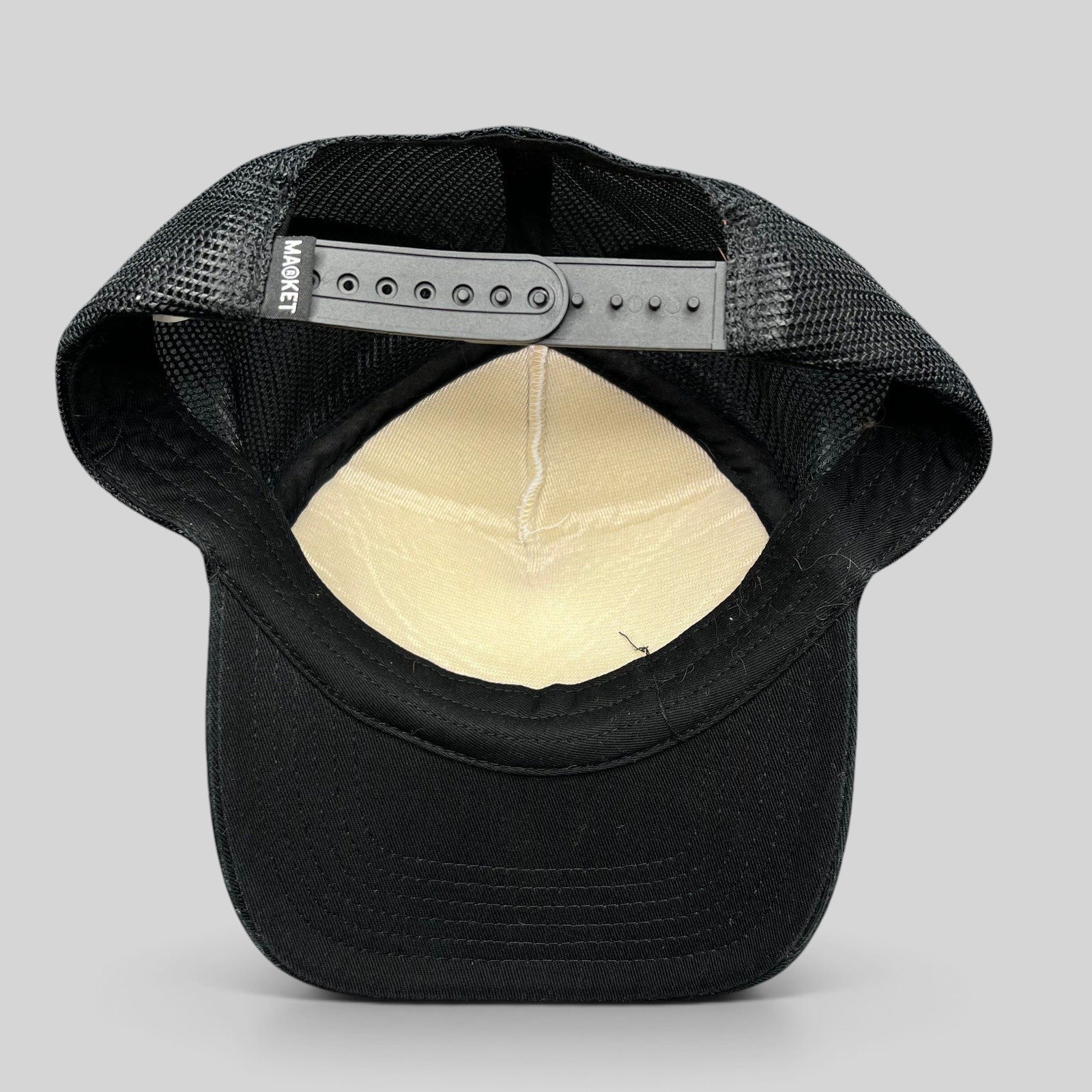 Raree Finds Coachella x Market black and white trucker hat showing the interior mesh lining and snapback closure