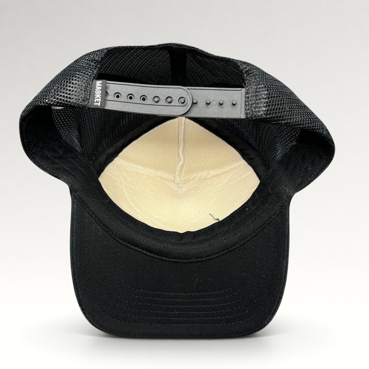 Raree Finds Coachella x Market black and white trucker hat showing the interior mesh lining and snapback closure