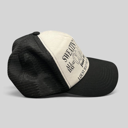 Raree Finds Coachella x Market black and white trucker hat with graphic text on the foam front and mesh back.