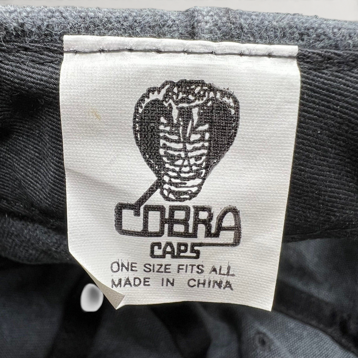 Raree Finds vintage 1998 Cobra Caps hat interior label showing brand logo and manufacturing details