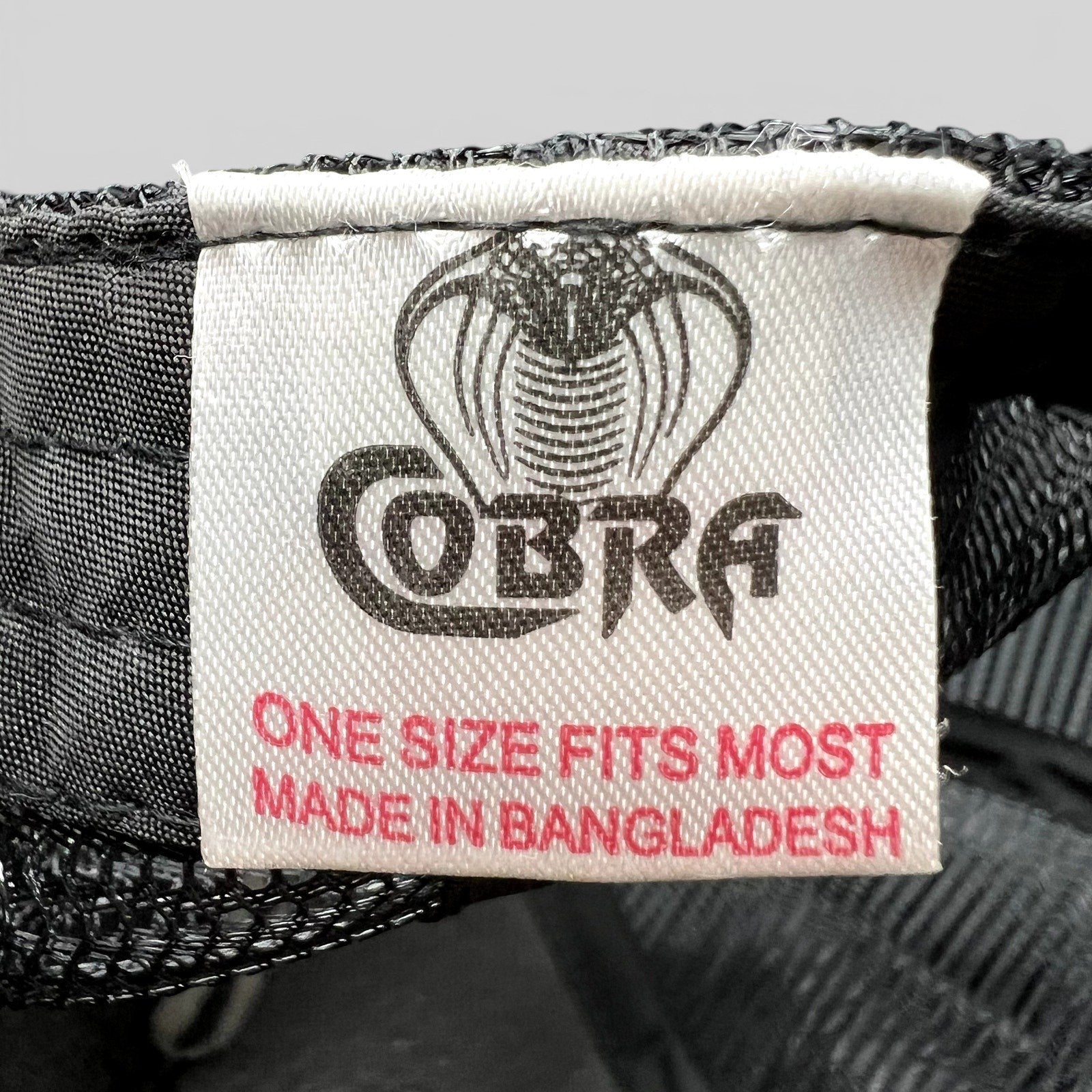 Raree Finds Cobra brand label inside a black trucker hat with white text and cobra logo, made in Bangladesh
