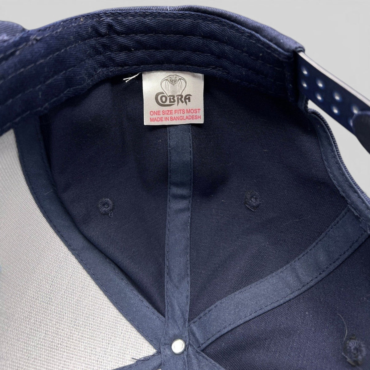 Interior view of a Raree Finds navy blue Cobra snapback hat showing the brand tag and structured foam construction.