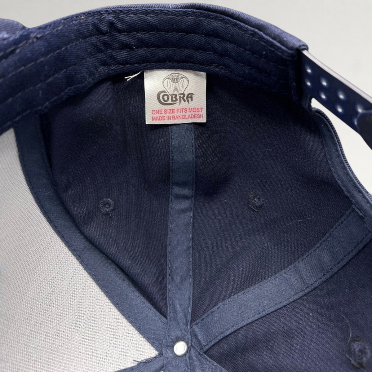 Interior view of a Raree Finds navy blue Cobra snapback hat showing the brand tag and structured foam construction.