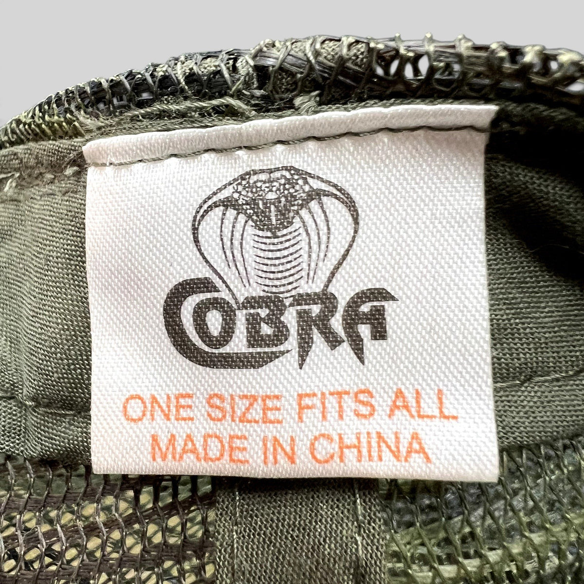 Raree Finds vintage Cobra brand tag inside an olive green and camo trucker hat with mesh backing