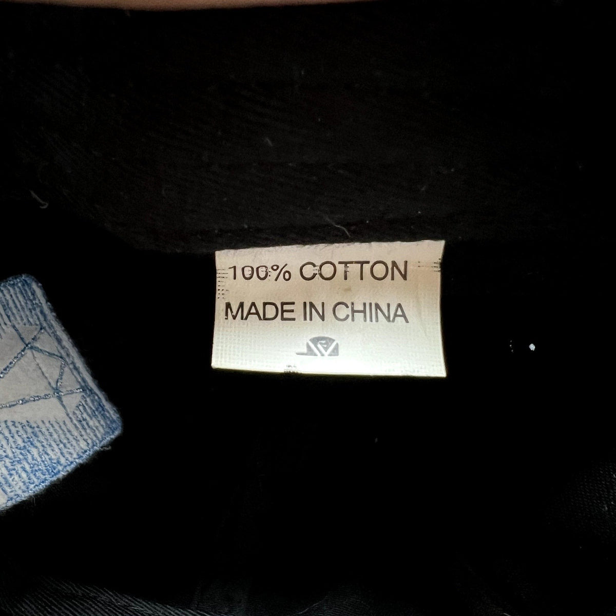 Raree Finds 100 percent cotton fabric care label inside a black hat with a blue embroidered diamond logo detail