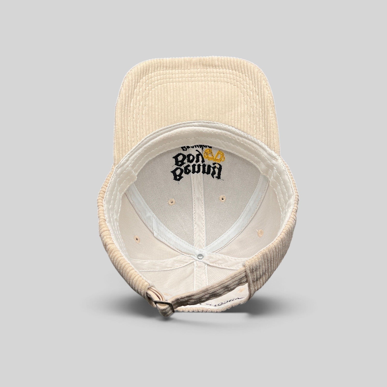 Raree Finds Benny Boy Brewing cream corduroy strapback hat showing the interior crown and adjustable metal buckle.