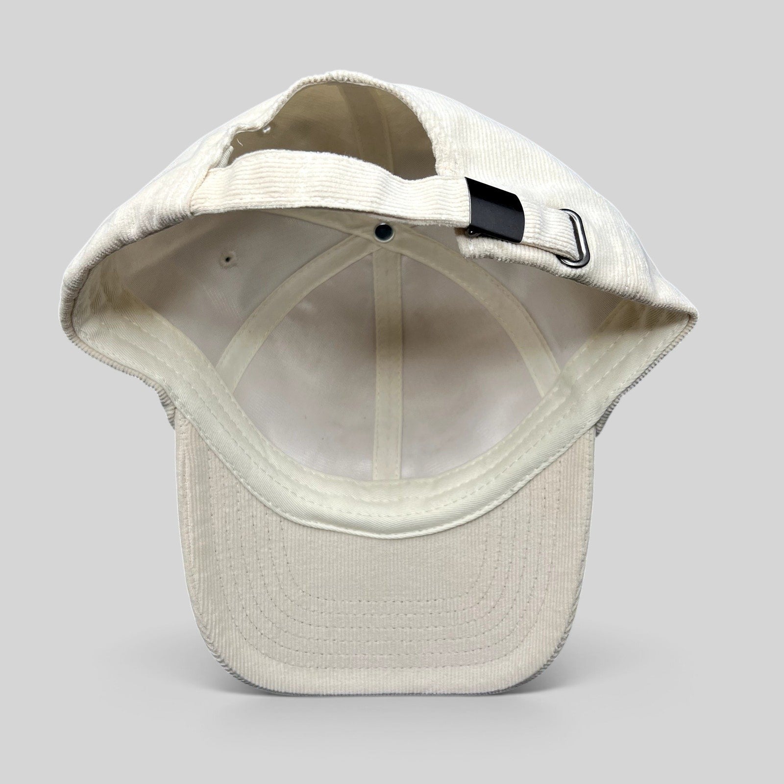 Raree Finds cream corduroy strapback hat showing the adjustable metal buckle closure and interior construction