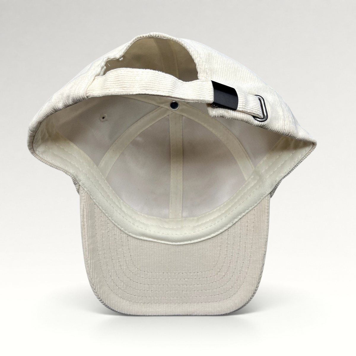 Raree Finds cream corduroy strapback hat showing the adjustable metal buckle closure and interior construction