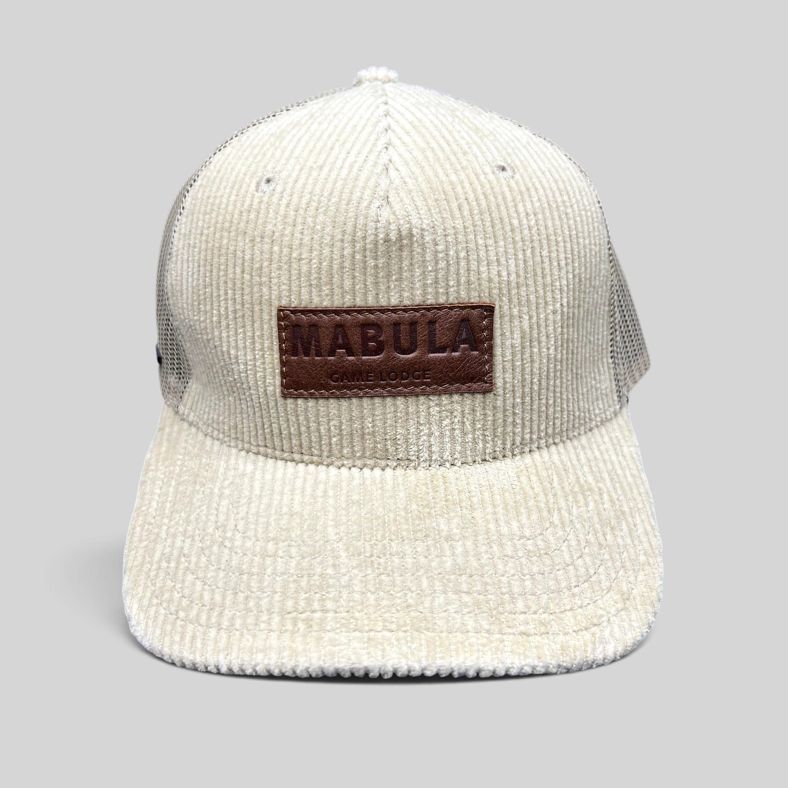 Raree Finds cream corduroy trucker hat with a brown leather Mabula Game Lodge patch and breathable mesh back panels.