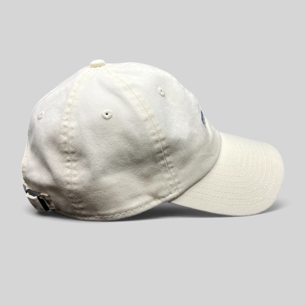 Raree Finds cream cotton New Era strapback hat with curved brim and relaxed unstructured crown, side profile view.