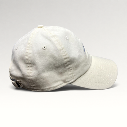 Raree Finds cream cotton New Era strapback hat with curved brim and relaxed unstructured crown, side profile view.