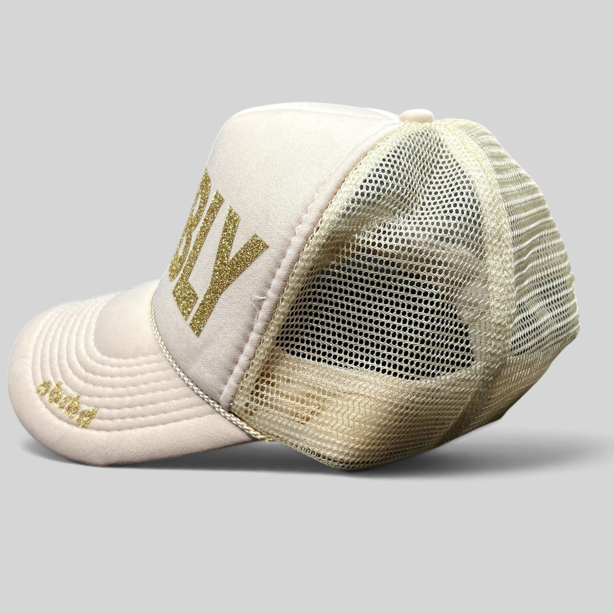 Raree Finds NBRHD Neighborhood Laguna cream trucker hat with gold glitter BUBBLY text and mesh back, side profile view.