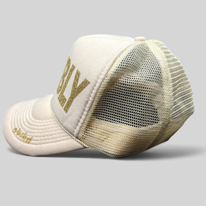 Raree Finds NBRHD Neighborhood Laguna cream trucker hat with gold glitter BUBBLY text and mesh back, side profile view.