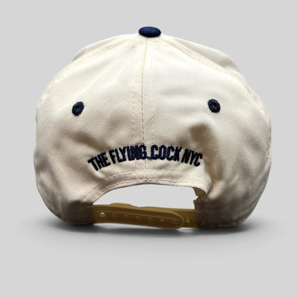 Raree Finds cream and navy snapback hat with The Flying Cock NYC embroidery on the back and adjustable strap.