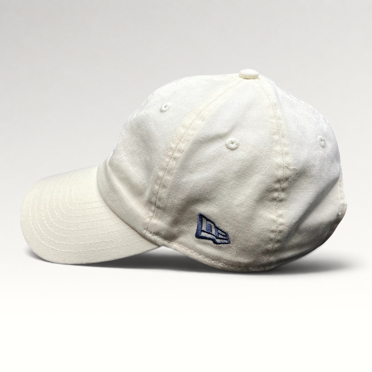 Raree Finds cream New Era strapback hat with side embroidered logo, unstructured cotton crown, and curved brim.
