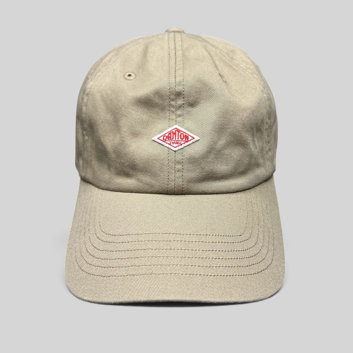 Raree Finds Danton khaki cotton twill strapback hat featuring an embroidered red diamond logo on a six-panel cap.