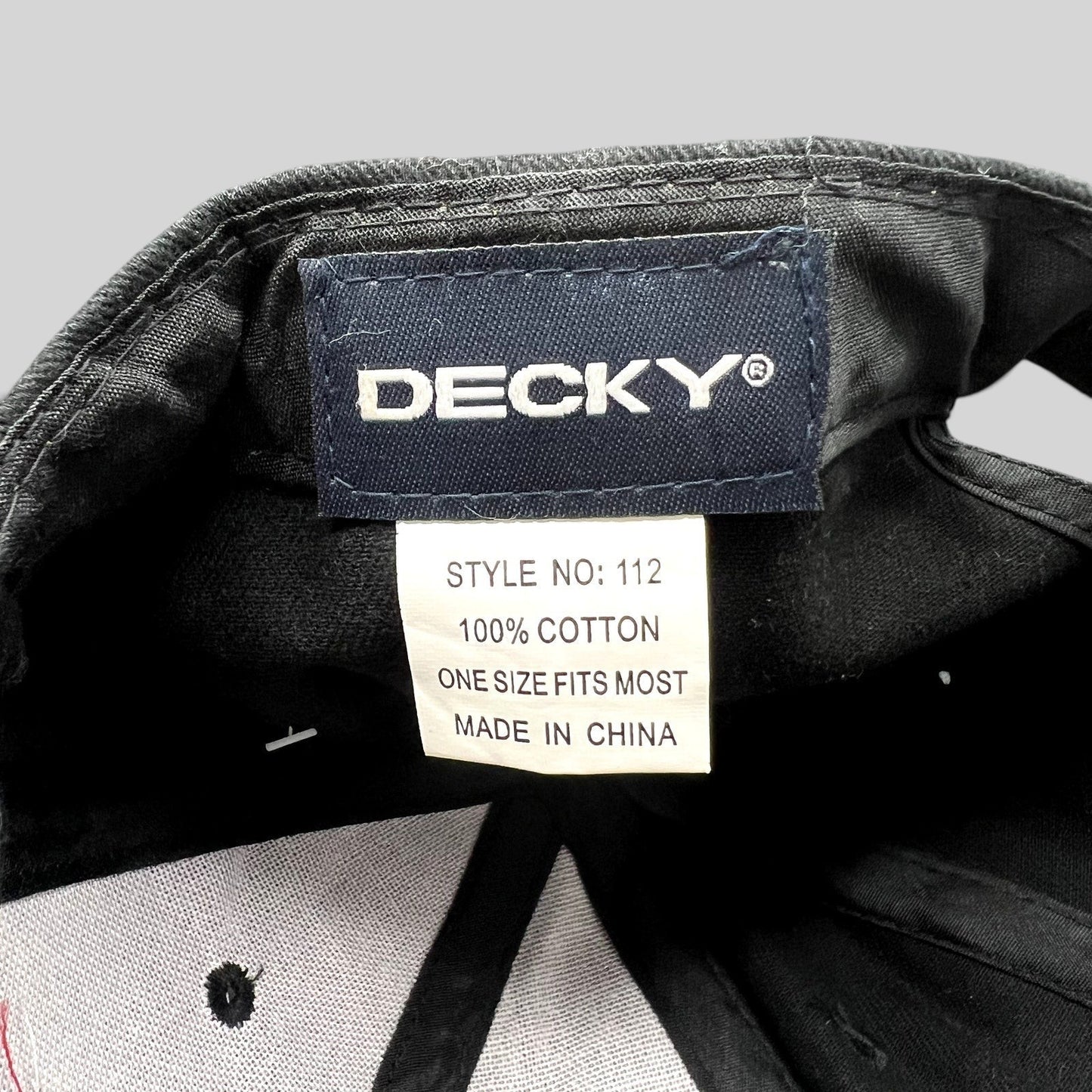 Raree Finds black Decky 112 cotton cap interior tag showing brand logo, material composition, and origin