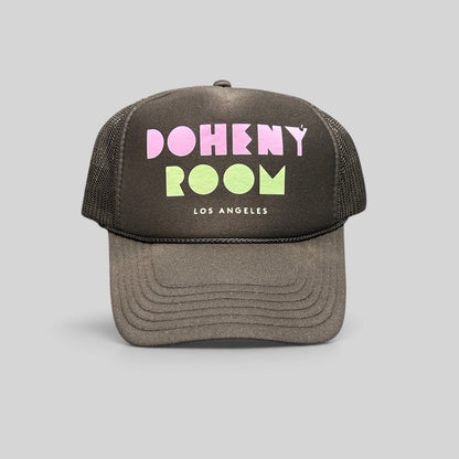 Raree Finds black mesh trucker hat with Doheny Room pastel logo on a structured foam front panel and curved brim.