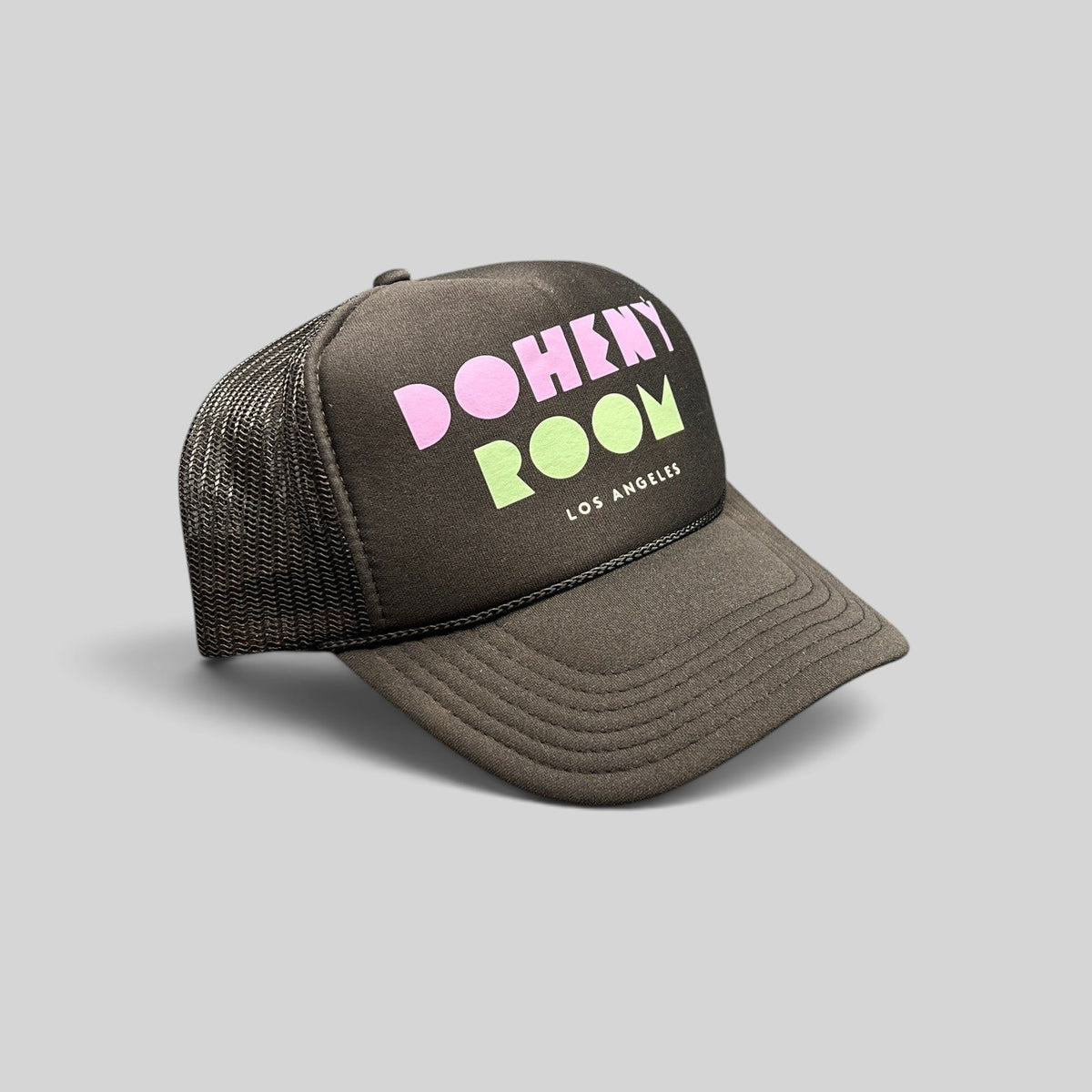 Raree Finds Doheny Room black mesh trucker hat with pastel logo on a structured foam front panel and curved brim.