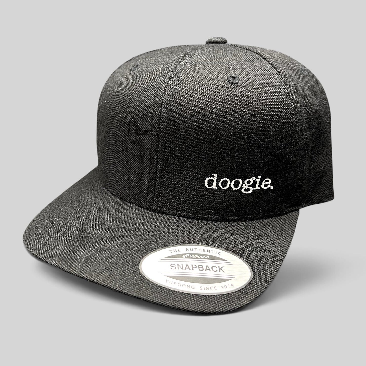 Raree Finds black Yupoong snapback hat with white embroidered doogie logo from the Doogie Kamealoha M.D. crew gift.