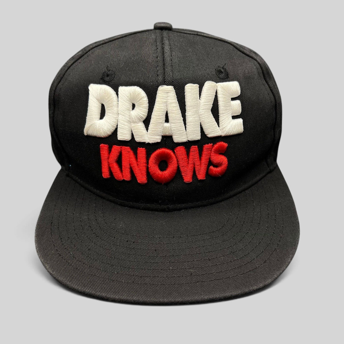 Raree Finds vintage black snapback hat with 3D embroidered white and red Drake Knows text on the front.