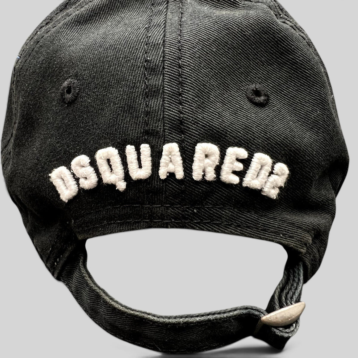 Raree Finds black DSQUARED2 strapback hat with white embroidered logo on the back and adjustable metal buckle closure.