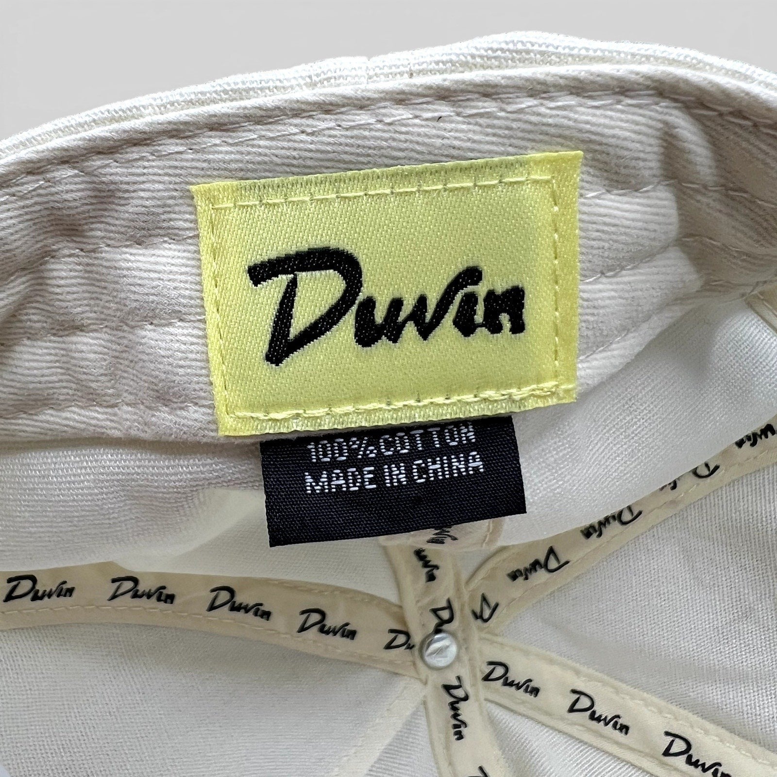 Raree Finds Duvin Beach Club hat interior showing yellow brand label and 100% cotton tag on white fabric