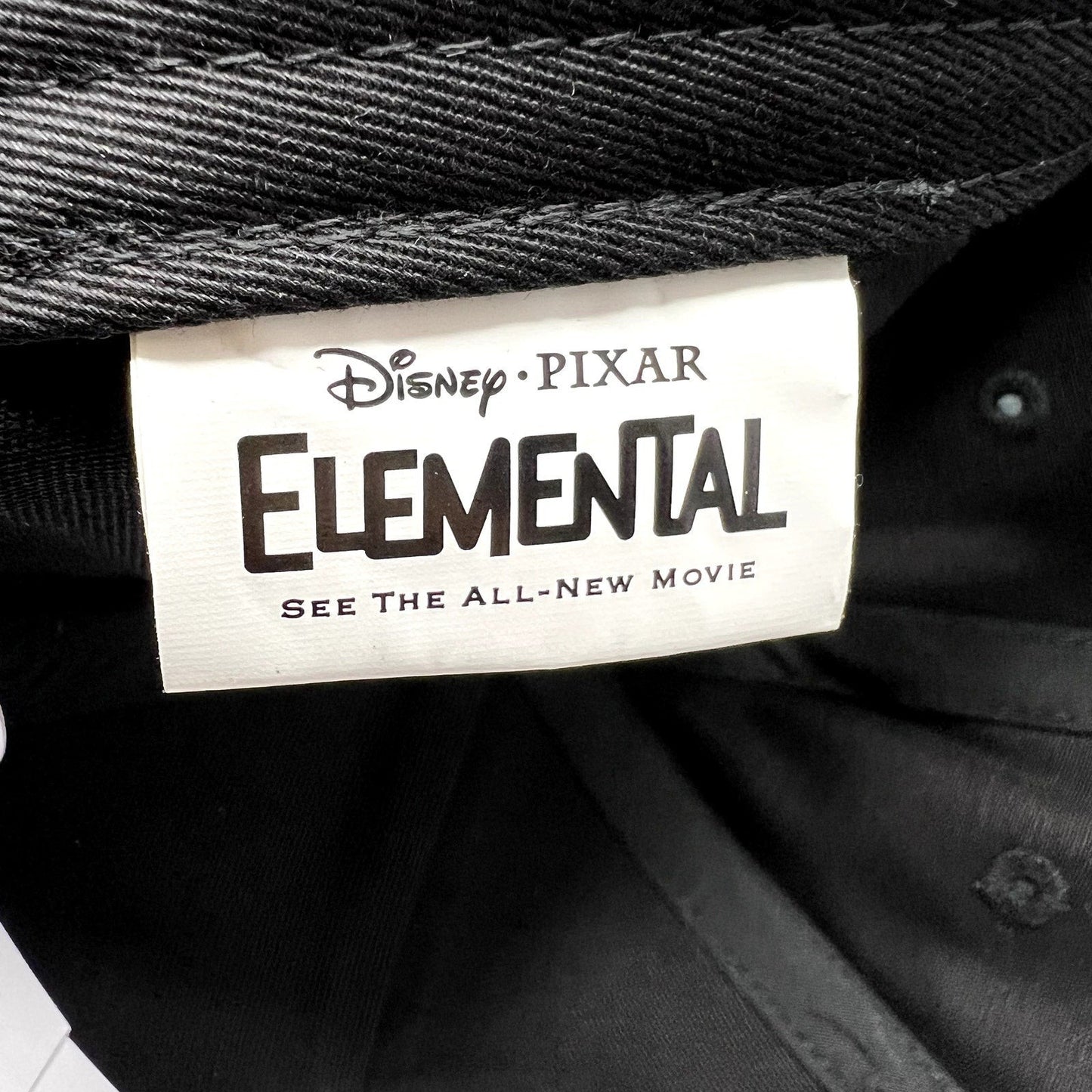 Raree Finds Disney Pixar Elemental movie promotional hat interior tag with black branding on a white fabric label