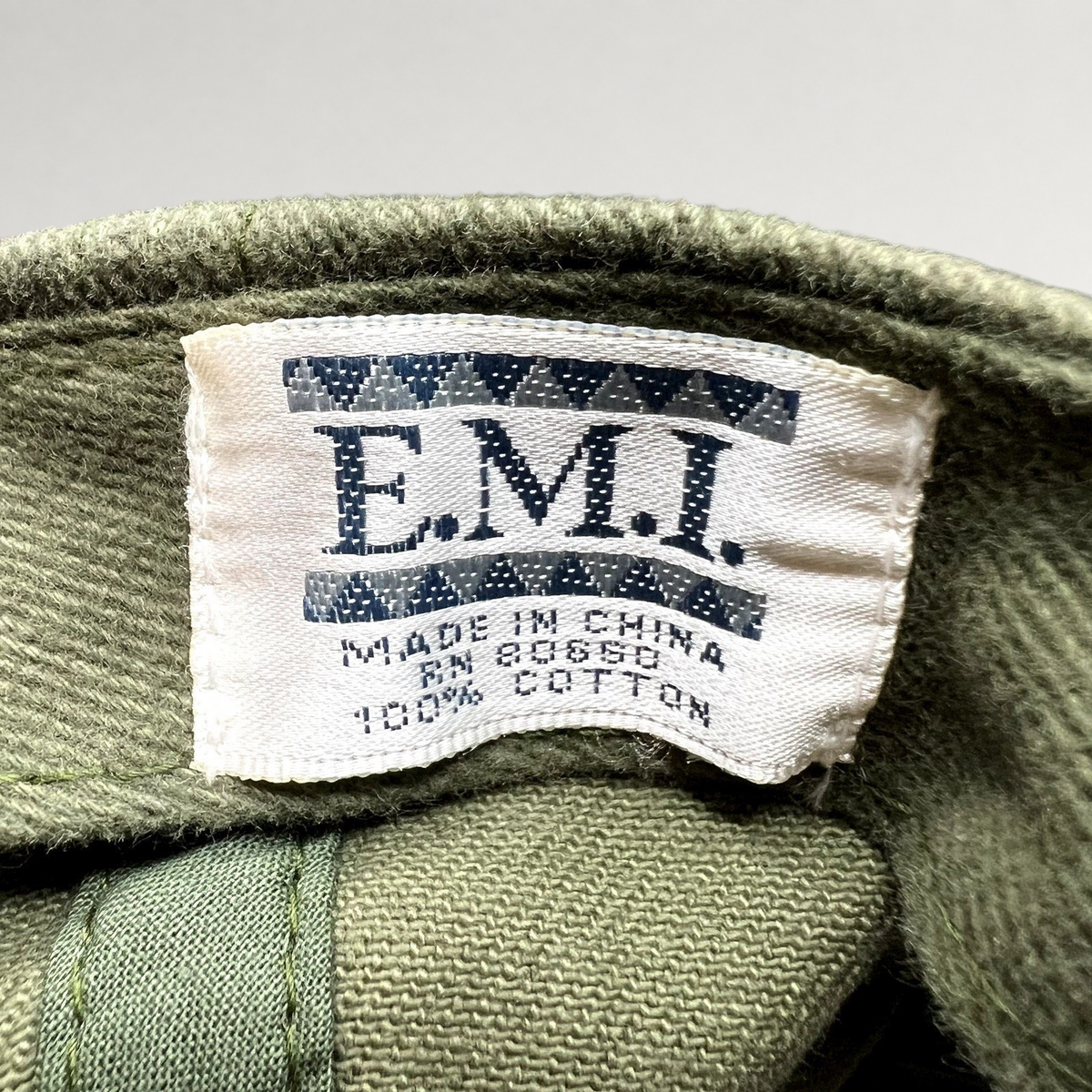 Raree Finds vintage EMI cotton hat interior tag showing brand logo, origin, and material details in olive green