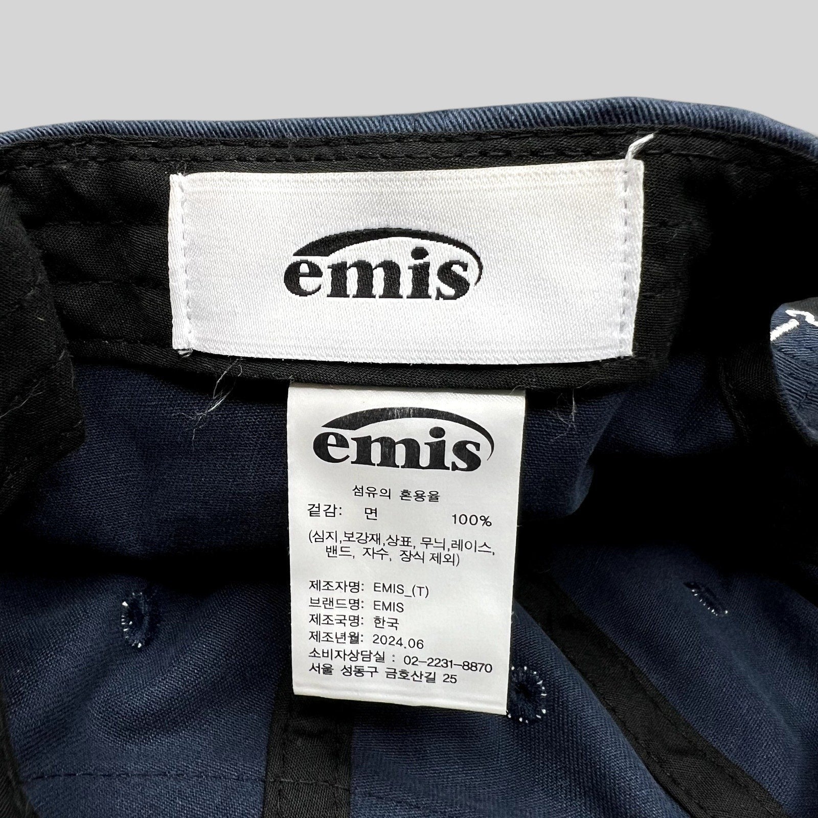 Raree Finds EMIS navy cotton strapback hat interior label and care tag showing 100 percent cotton composition