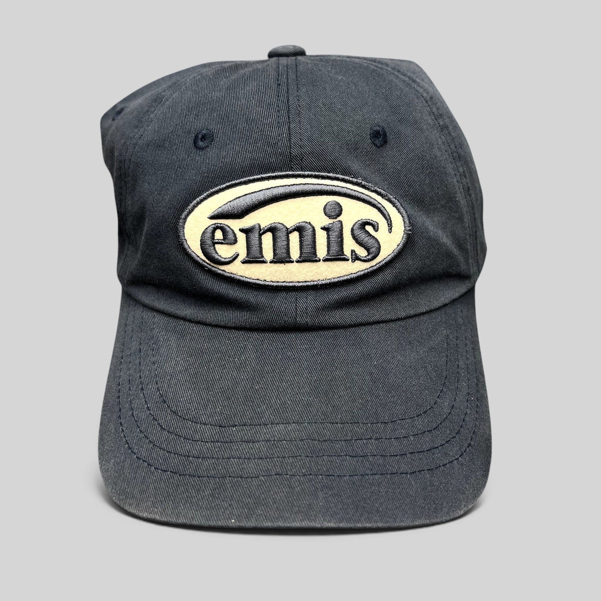 Raree Finds navy cotton strapback hat by EMIS featuring a cream oval logo embroidery on the front