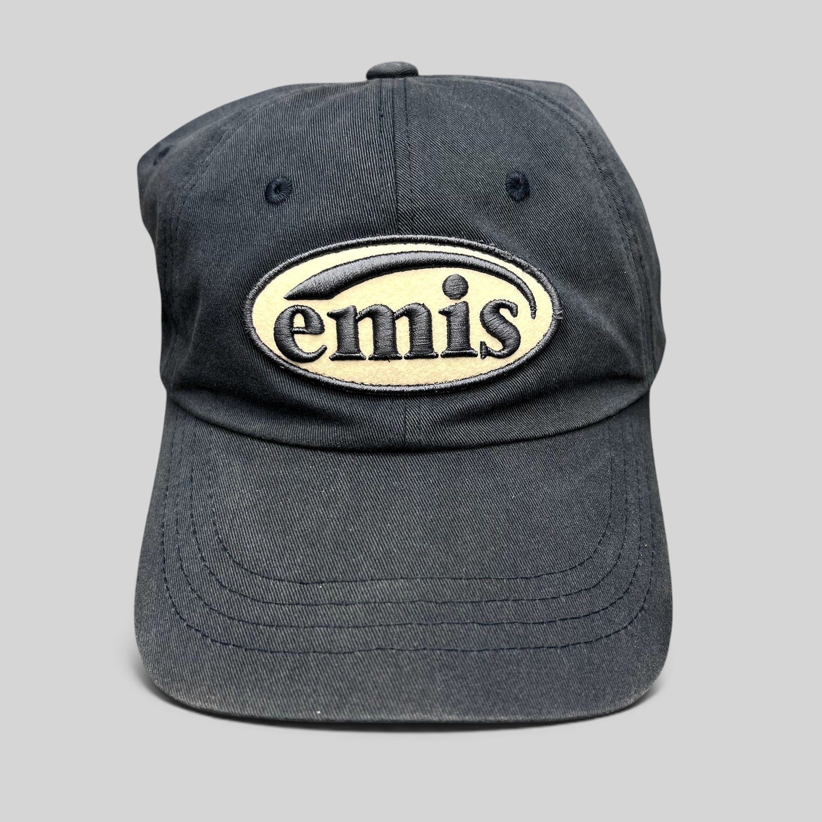 Raree Finds navy cotton strapback hat by EMIS featuring a cream oval logo embroidery on the front