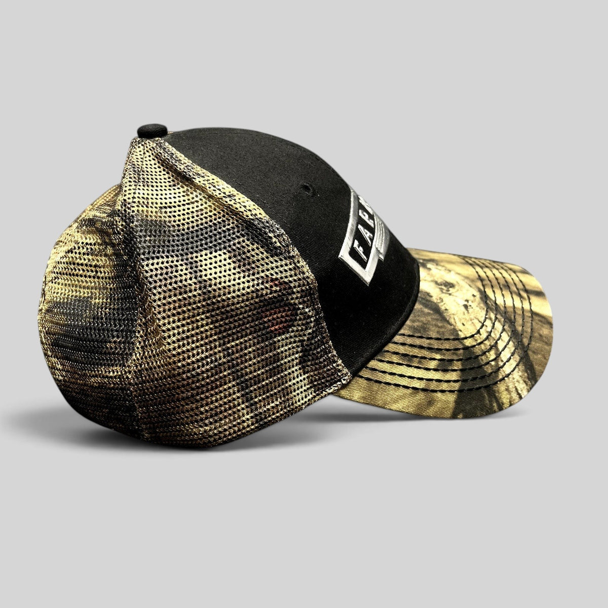 Raree Finds Farmall trucker hat with black cotton crown, camouflage mesh back, and metallic logo patch on curved brim