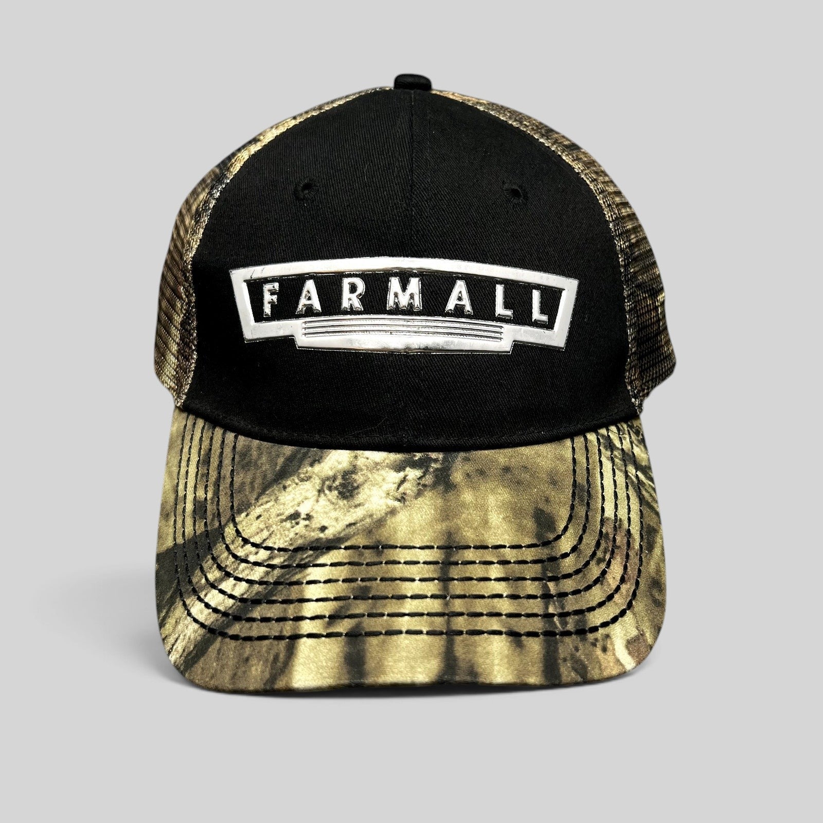 Raree Finds Farmall trucker hat with black cotton crown, camouflage brim, mesh back, and metallic logo patch