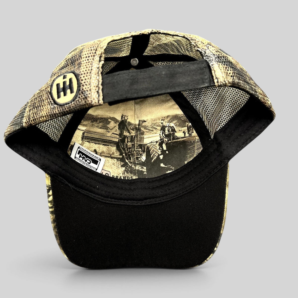 Raree Finds Farmall trucker hat showing interior vintage farm scene print, camo mesh back, and black cotton brim
