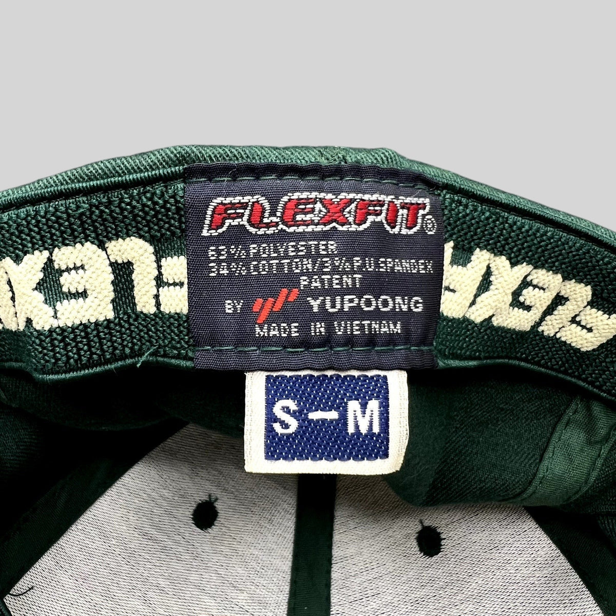 Raree Finds forest green Flexfit hat interior label showing Yupoong branding and size S/M tag
