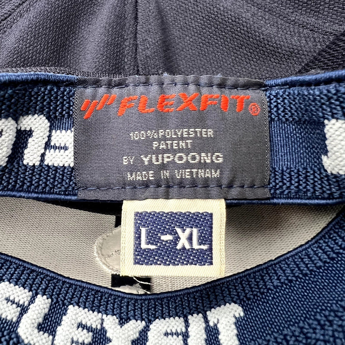 Raree Finds navy blue Flexfit by Yupoong hat interior label showing size L/XL and polyester material details