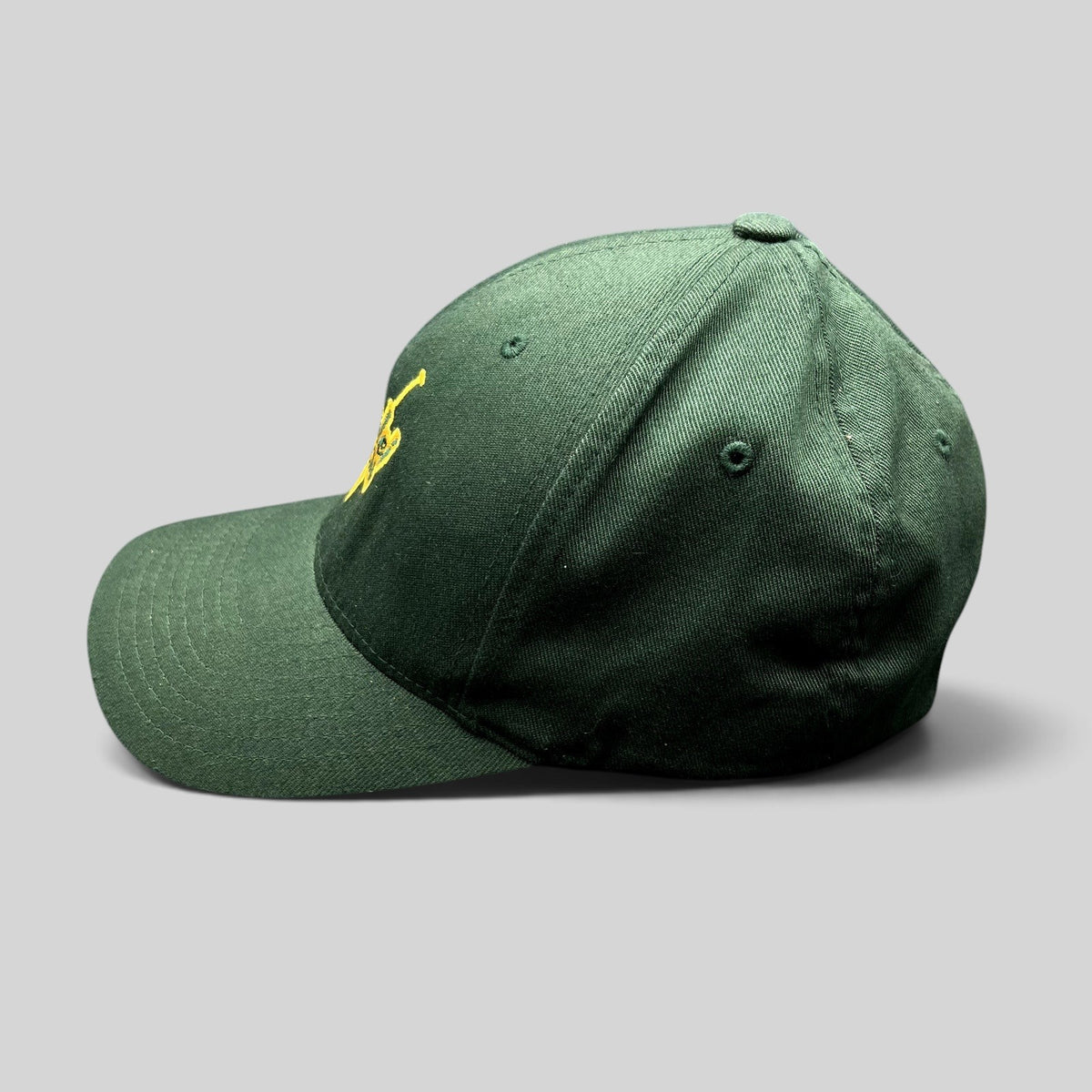 Raree Finds forest green Hanalei Canoe Club Flexfit hat with gold embroidered paddle logo, side profile view.