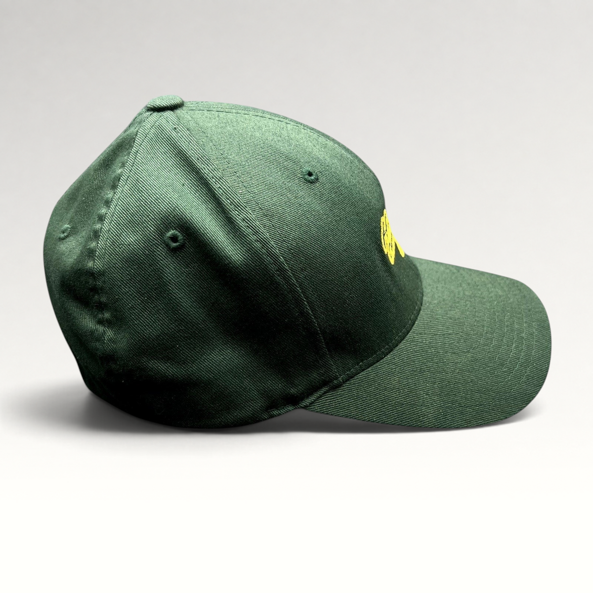 Raree Finds forest green Hanalei Canoe Club Flexfit hat with gold embroidered paddle logo, side profile view.